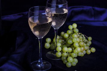 Glasses of wine and grapes on a dark background