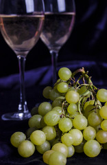 Glasses of wine and grapes on a dark background