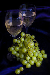 Glasses of wine and grapes on a dark background