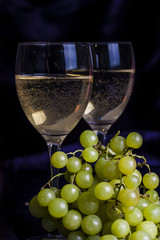 Glasses of wine and grapes on a dark background