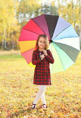 Beautiful little girl child with colorful umbrella in autumn day