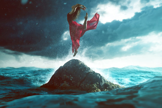 Woman dances on a rock in the sea