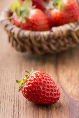fragola in primo piano con cestino di fragole sullo sfondo