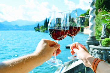 Two wineglasses in the hands. Varenna town at the lake Como, Ita