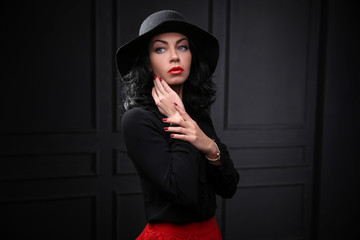 A model in a fashion dress and hat posing on the black background