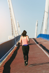 Obraz premium Young fitness woman runner running on city bridge.