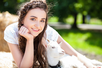 Young woman hugging a small lamb at farm