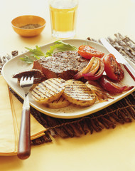 Grilled steak and potato with grilled tomatoes and onion.