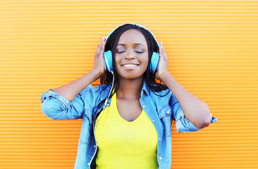 Happy smiling young african woman with headphones enjoying liste