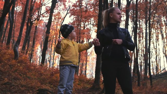 Beautiful mother and little child in the autumn forest. Boy shout