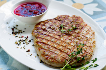 Delicious fried steak with sauce and spices on a white plate