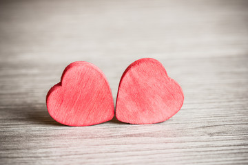 Two wooden hearts on wooden surface.