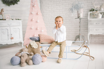 Baby boy alone on sled playing xmas decorated studio