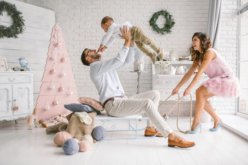 Young family having fun with sled in white studio