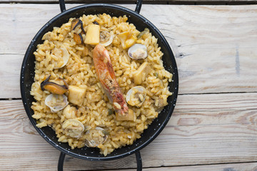 Vegetable paella with seafood on a wooden background