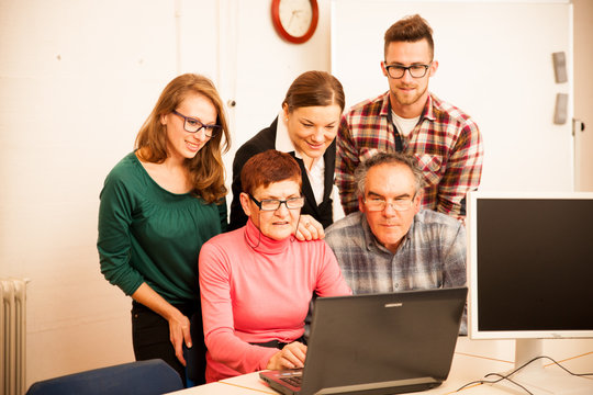 Group Of Adults Learning Computer Skills. Intergenerational Tran