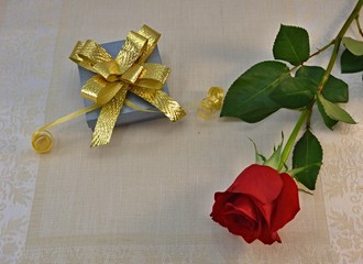 gift and red rose on the table