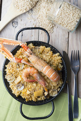 Vegetable paella with seafood on a wooden background