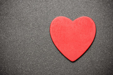 Red wooden heart on black surface. Empty copy space background.