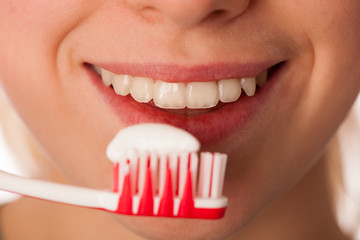 Woman holding toothbrush in front of teeth promoting mouth hygie