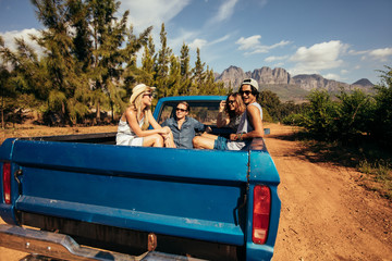 Group of friends sitting at the back of a pick up car