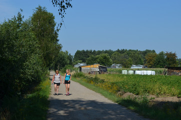 Woman and girl walking on an asphalt road in rural area