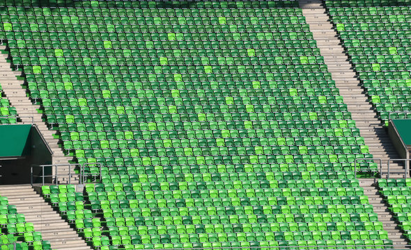 Green plastic stadium chairs on bleachers in row