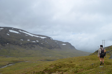Fototapeta na wymiar Hiker standing on a ridge overlooking valley in Swedish Lapland