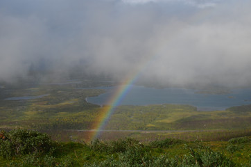 Clouds, rainbow and sunshine over valley in subarctic mountains, Swedish Lapland