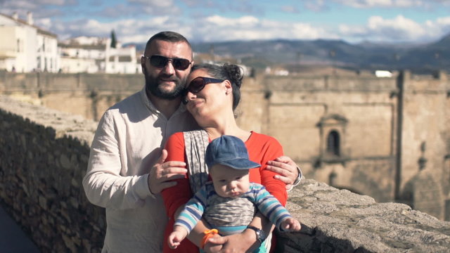 Portrait of happy family hugging and kissing on the Ronda bridge in Andalusia
