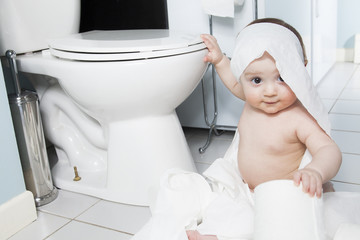 Toddler ripping up toilet paper in bathroom