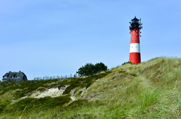 Leuchtturm mit Reethaus am Strand von Hörnum auf Sylt..