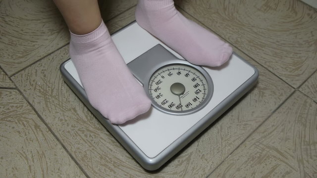 Female with Pink Socks Standing on Weight Scale With Sequence Angles. No Logos Visible just a generic weight disclaimer.