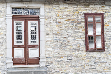 Old wooden door with glass ornated by metal bar and window in sonemasonry building. Pano Lefkara, Cyprus.
