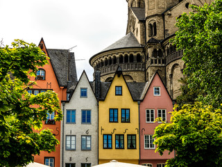 Eine Reihe bunter  Häuser am Rheinufer vor Groß St.Martin Kirche in Köln