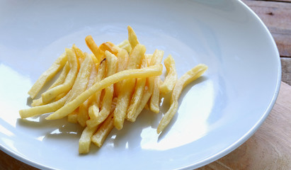 French fries on white dish on wooden background