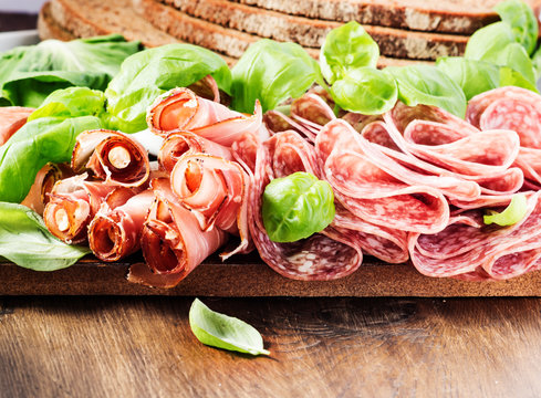  italian speck  and salami on  dark old wooden background.