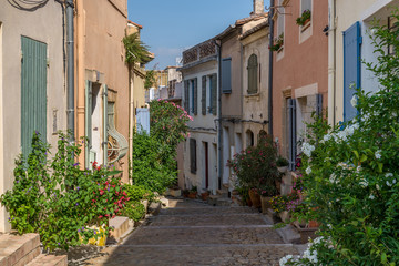Fototapeta na wymiar Bended street with coloured houses and flowers in Arles, France on a sunny day in summer
