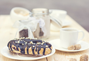Chocolate cake (eclair) with cup of coffee.  profiteroles with chocolate cream. Tonned photo.