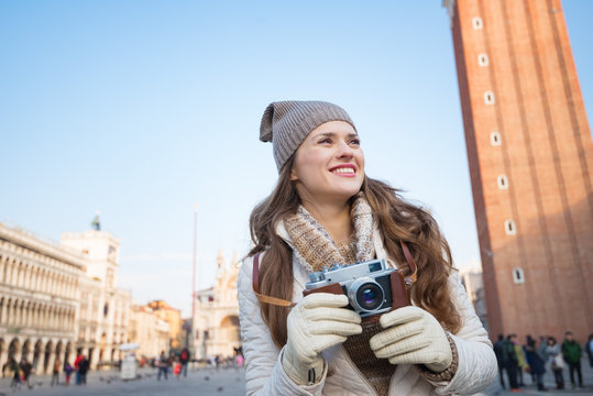 Happy woman holding retro photo camera on Piazza San Marco