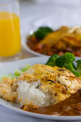 Japanese curry, a colourful dish of Japanese curry rice with omelette and broccoli with a glass of orange juice.