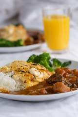 Japanese curry, a colourful dish of Japanese curry rice with omelette and broccoli with a glass of orange juice.