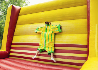 Young woman in plastic dress in a bouncy castle imitates the fly