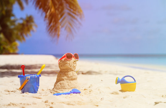 Sandy snowman and toys at tropical beach
