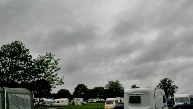 Timelapse of dark rainclouds sweeping across the sky over a caravan and camping park in England.