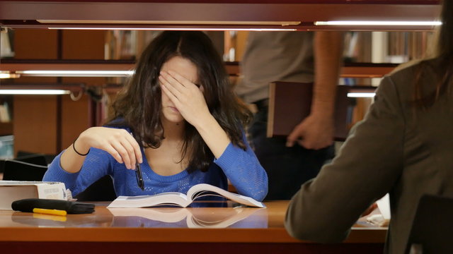 Young woman trying to study at the library. She looks very frustrated. Dolly. UHD