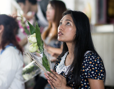 Young Asian woman fervently praying in a Buddhist monastery