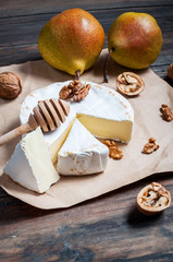 Camembert cheese with walnuts, honey and pears on rustic table