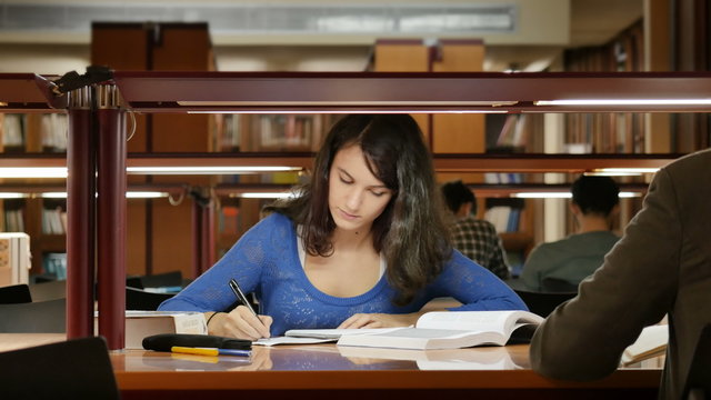 Young woman studying at the library, very concentrated. Dolly. UHD