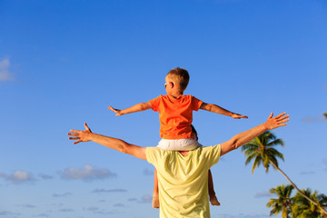 happy father and little son on shoulders play at sky